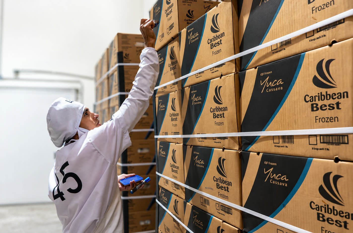 Farmers Imports worker checking stacked pallets of Caribbean Best frozen yuca boxes in cold storage